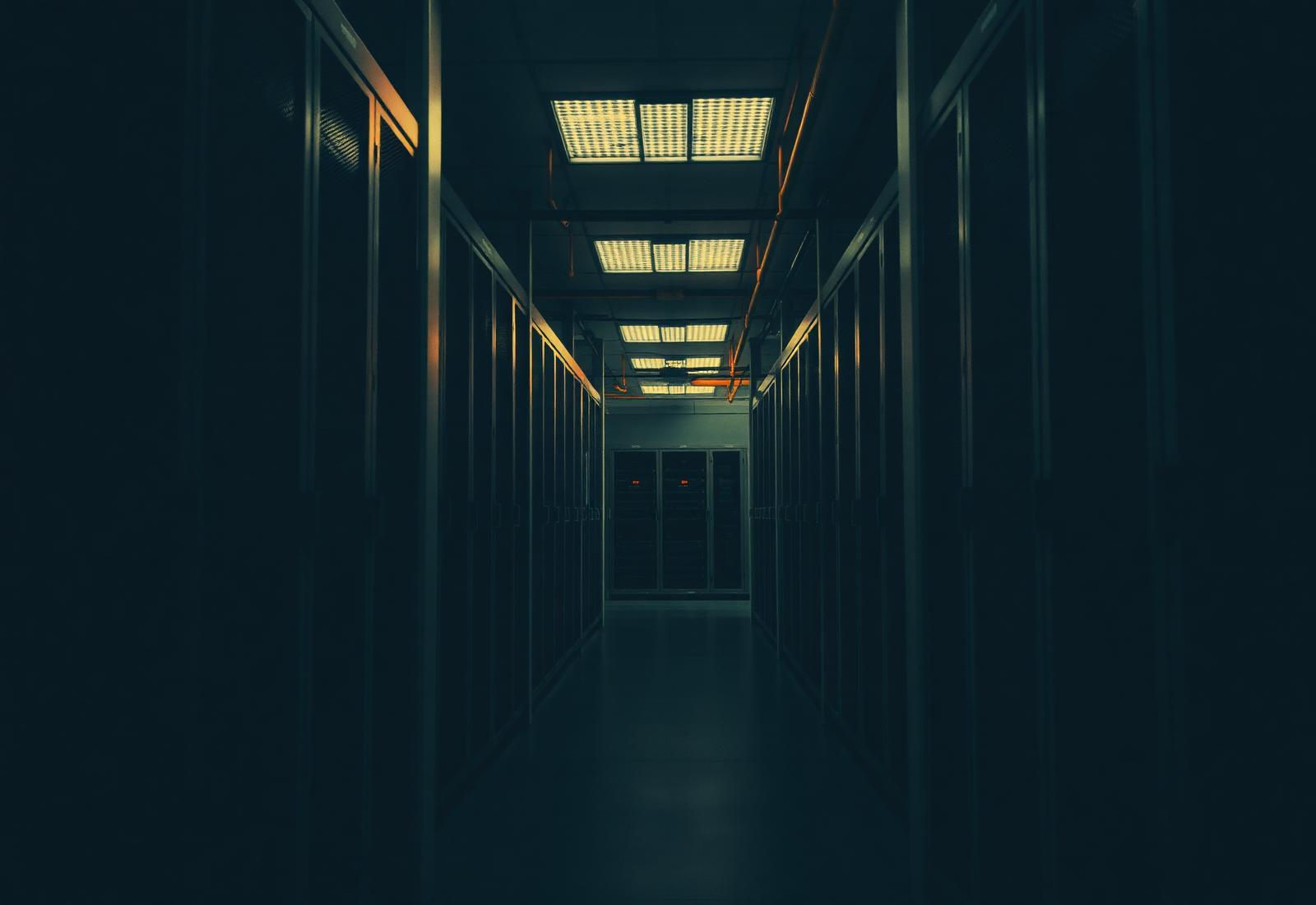 A quiet, warmly lit corridor of server racks representing the infrastructure BLOCK AND RESERVE LTD engineers and operates.
